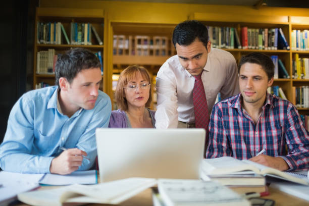 istock Mature students with teacher and laptop in library 846668512
