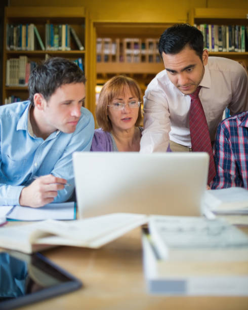 istock Mature students with teacher and laptop in library 846668548