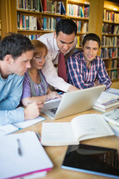 istock Mature students with teacher and laptop in library 846668676