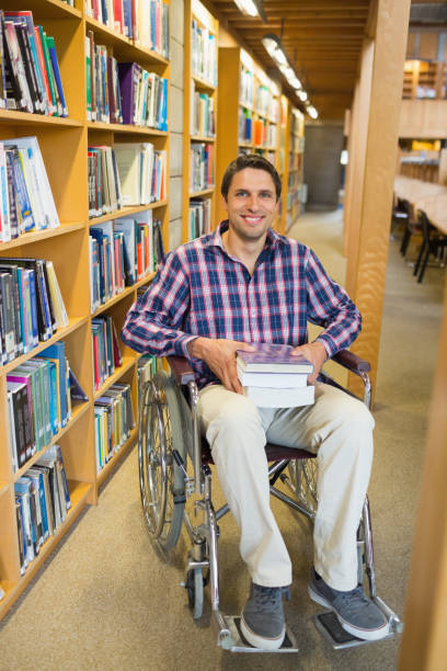 istock Man in wheelchair by bookshelf in library 846674294