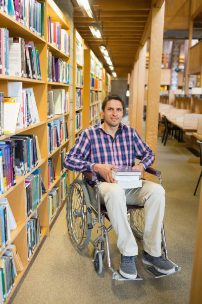 istock Man in wheelchair by bookshelf in the library 846674308
