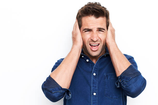 Turn it down Guy in studio with hands over ears, portrait hands covering ears stock pictures, royalty-free photos & images