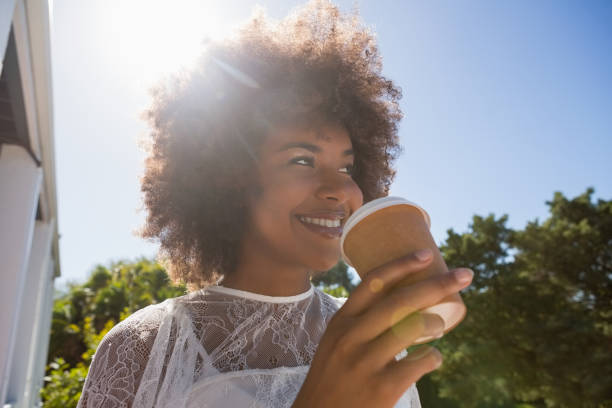 istock Smiling young woman looking away while holding disposable cup 846690474