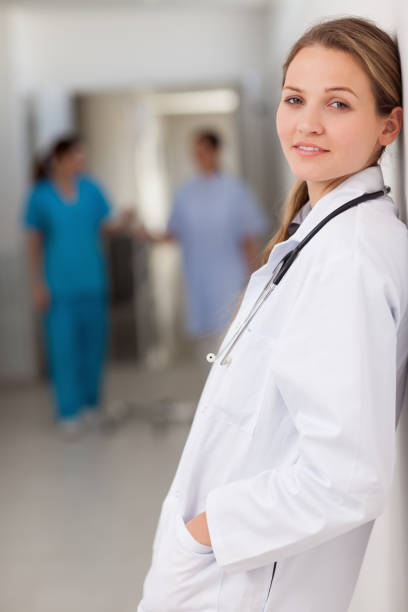 istock Smiling doctor standing against a wall with her hands in her pockets 846693074
