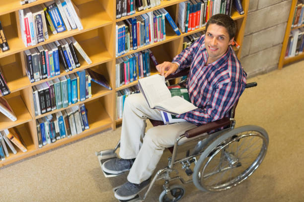 istock Man in wheelchair by bookshelf in the library 846705286