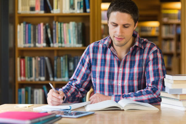 istock Male student writing notes at desk in the library 846707504