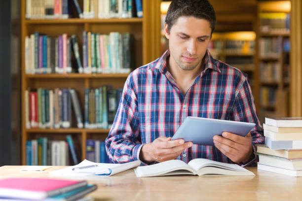 istock Male student using tablet PC at desk in the library 846707528