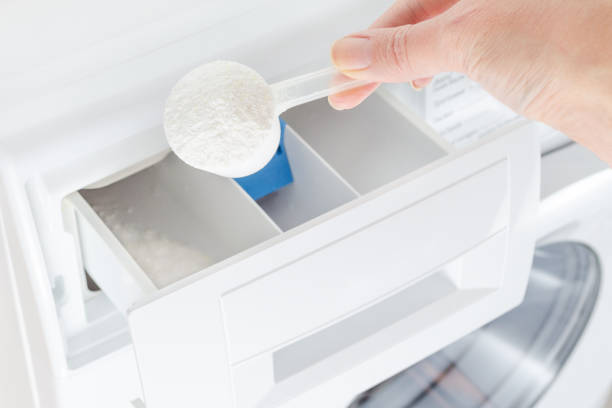 washing powder, detergent in a cup and womans hand, washing machine, selective focus