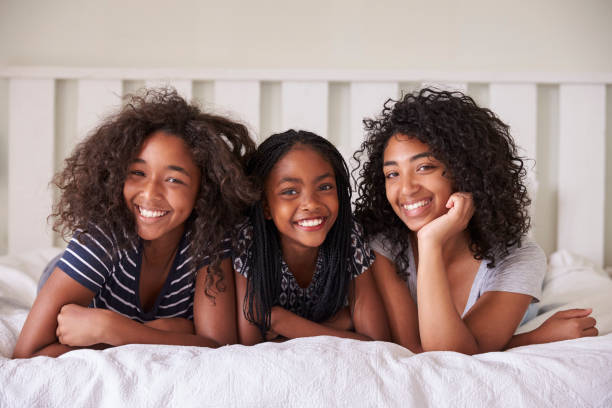 retrato de tres hermanas adolescentes acostado en cama en casa - child group of people teenager sibling fotografías e imágenes de stock