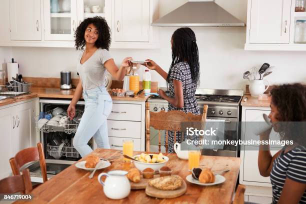 Three Teenage Girls Clearing Table After Family Breakfast Stock Photo - Download Image Now