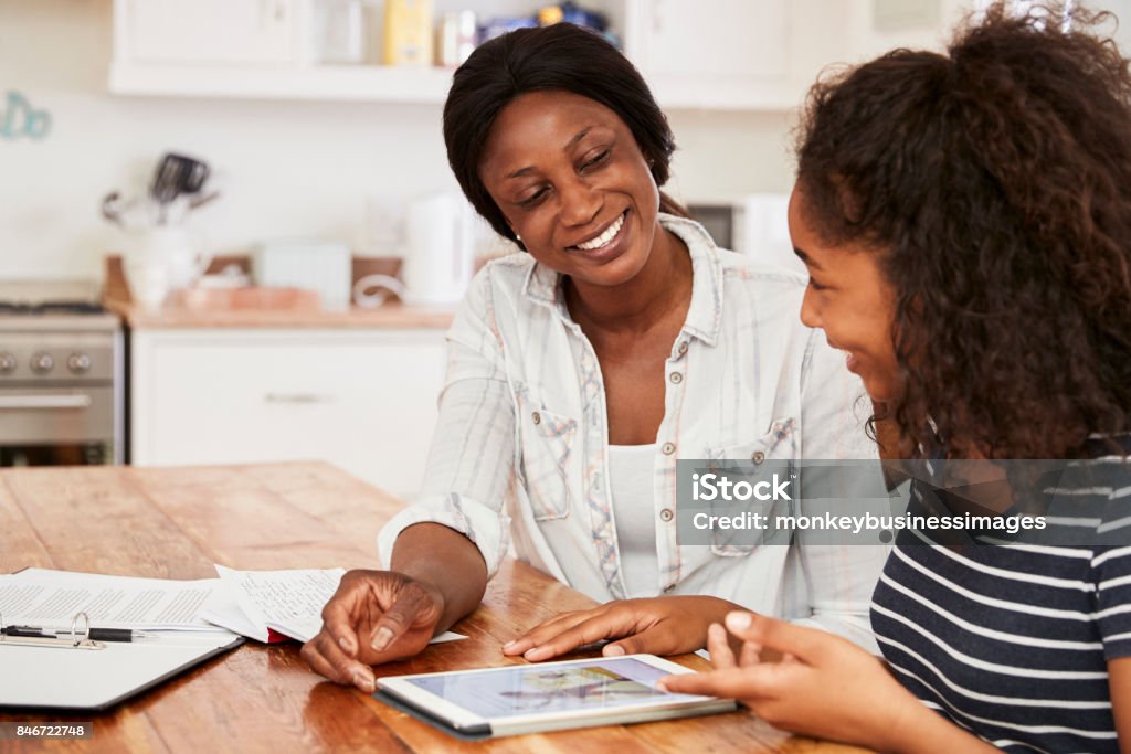 Mutter hilft Teenager-Tochter bei den Hausaufgaben mit Digital-Tablette - Lizenzfrei Teenager-Alter Stock-Foto