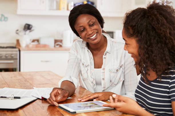 Mother Helps Teenage Daughter With Homework Using Digital Tablet Mother Helps Teenage Daughter With Homework Using Digital Tablet homework stock pictures, royalty-free photos & images