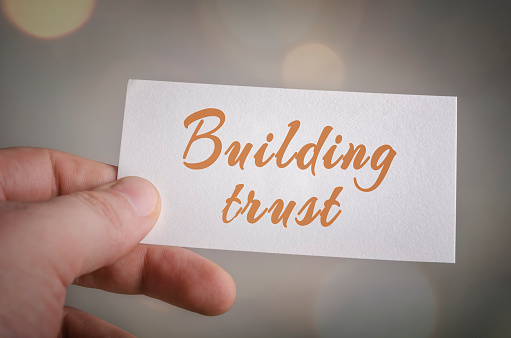 Building trust card in hand with bokeh lights background