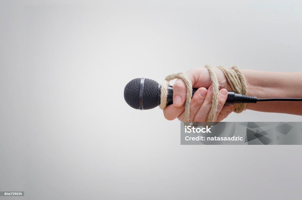 Hand with microphone tied with rope Hand with microphone tied with rope, depicting the idea of freedom of the press, idea of the repression of the mass media or freedom of expression Censorship Stock Photo