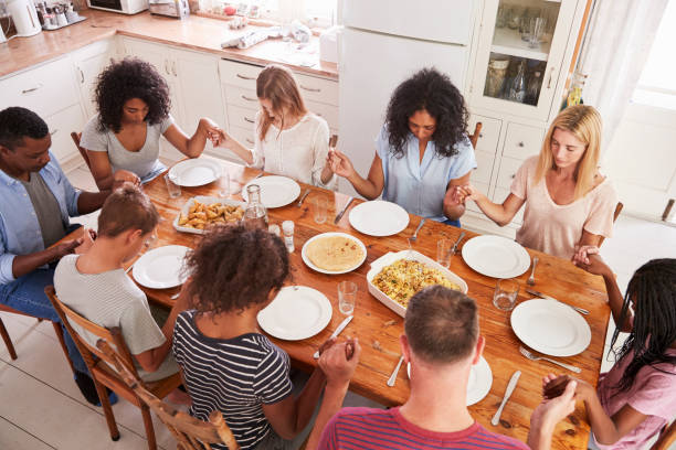 istock Two Families Saying Grace Before Eating Meal Together 846729288