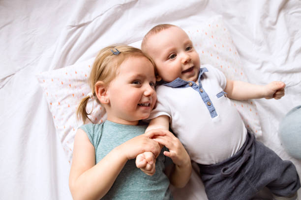 침대에 누워 그녀의 아기가 동생과 함께 귀여운 작은 소녀. - lying on back child shirt love 뉴스 사진 이미지
