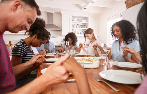 istock Two Families Saying Grace Before Eating Meal Together 846730454