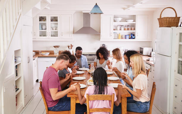 istock Two Families Saying Grace Before Eating Meal Together 846730456