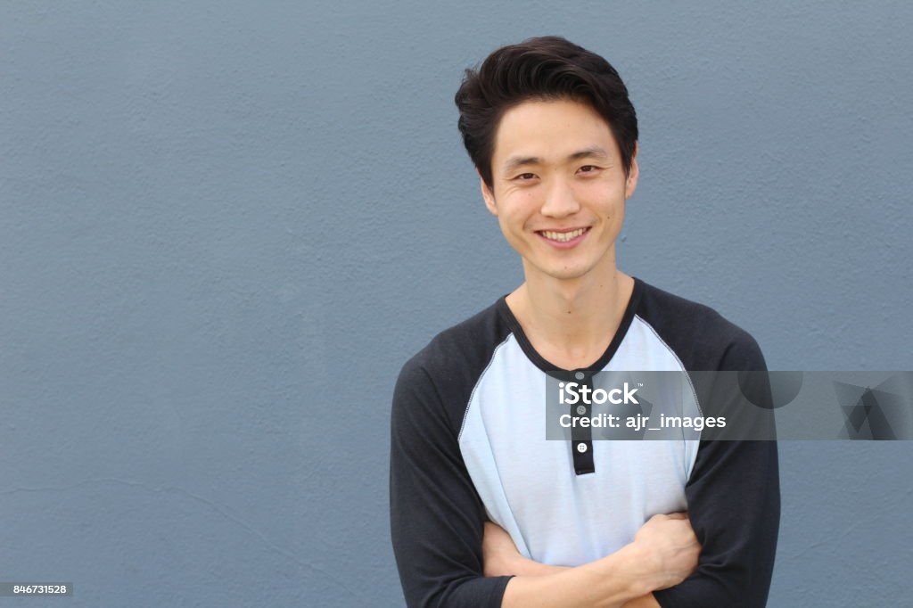 Young Asian male smiling and laughing with arms crossed Young Asian male smiling and laughing with arms crossed. Men Stock Photo