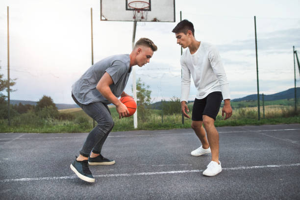 ハンサムな 10 代の少年の遊び場で野外バスケット ボールで遊ぶ。 - basketball teenager nature outdoors ストックフォトと画像