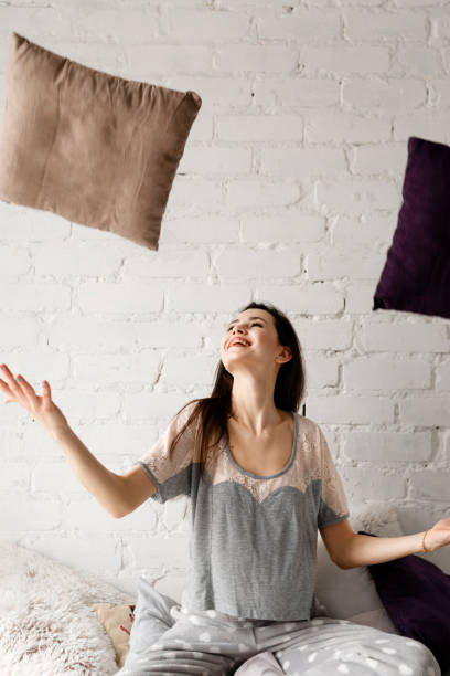 istock Joyful woman throwing up pillows 846738792