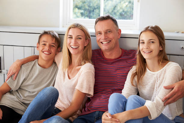 ritratto di famiglia sorridente rilassante sul sedile di casa - four people foto e immagini stock