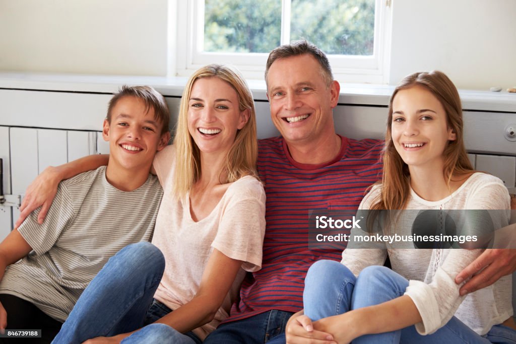 Portrait Of Smiling Family Relaxing On Seat At Home Family Stock Photo
