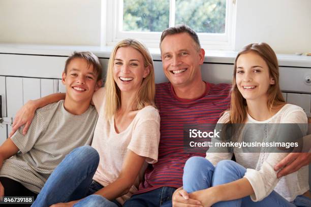 Portrait Of Smiling Family Relaxing On Seat At Home Stock Photo - Download Image Now