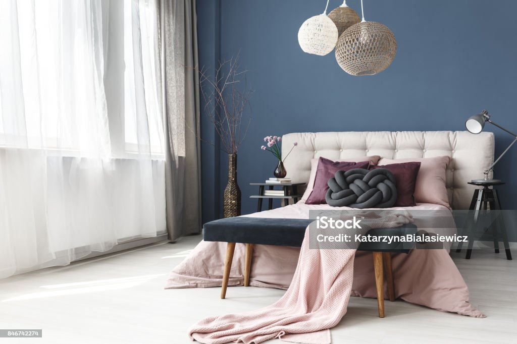 Violet pillows on bed black braided pillow and violet pillows with pink overlay on king-size bed in stylish bedroom Apartment Stock Photo