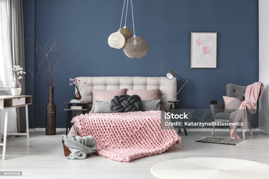 Grey armchair with pink blanket Grey armchair with pink blanket and pastel pillow in bedroom with subtle painting on blue wall Bedroom Stock Photo