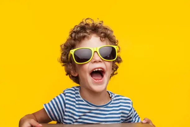 Photo of Adorable kid in bright sunglasses on orange