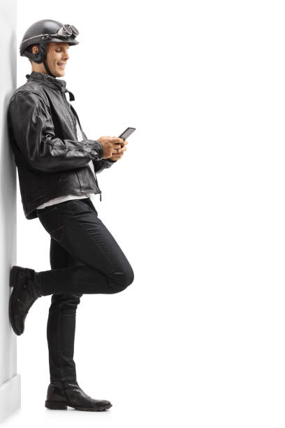 biker apoyado contra una pared y usar un teléfono - isolated on white full length red protection fotografías e imágenes de stock
