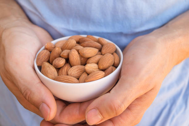White ceramic bowl full of almonds in the man's hands