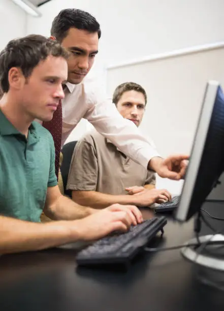 Photo of Teacher and mature students in computer room