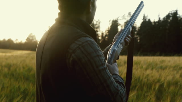Hunter gets ready to shoot a weapon at golden hour (slow motion)