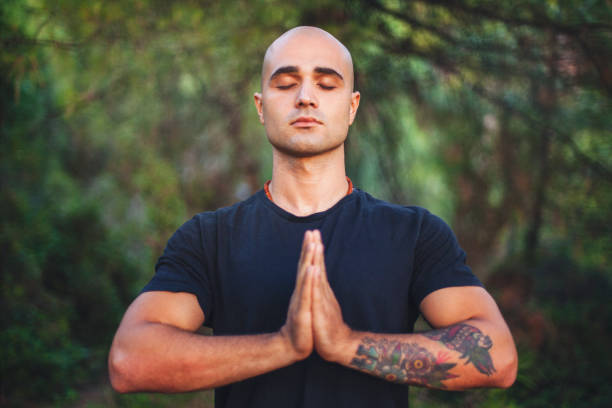 Young man doing yoga at park Confident young man doing yoga at park yoga instructor stock pictures, royalty-free photos & images