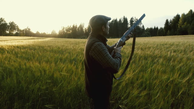 Hunter shoots a weapon at golden hour