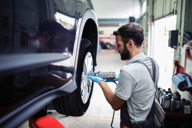 tire changing at car service - mechanic auto repair shop auto mechanic repairing imagens e fotografias de stock