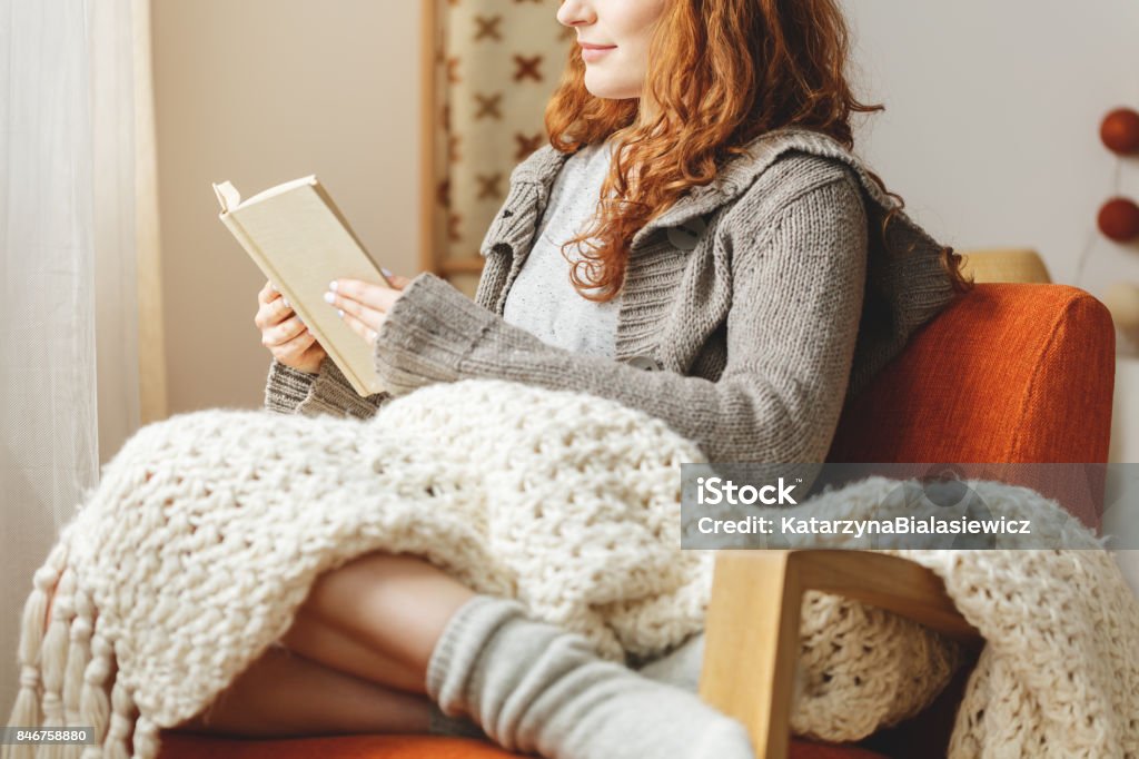 Woman reading a book Happy young woman reading a book in a chair Reading Stock Photo