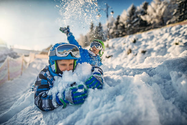 deux petits garçons dans des tenues de ski jouant dans la neige fraîche - skiing sports helmet powder snow ski goggles photos et images de collection