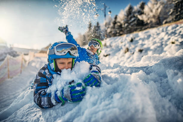 due ragazzini in abiti da sci che giocano nella neve fresca - skiing sports helmet powder snow ski goggles foto e immagini stock