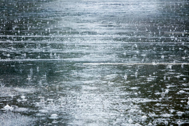 estrada alagada durante a chuva pesada com salpicos de pingos de chuva - chuva torrencial - fotografias e filmes do acervo