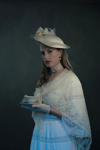 Portrait of young victorian woman holding cup of tea.