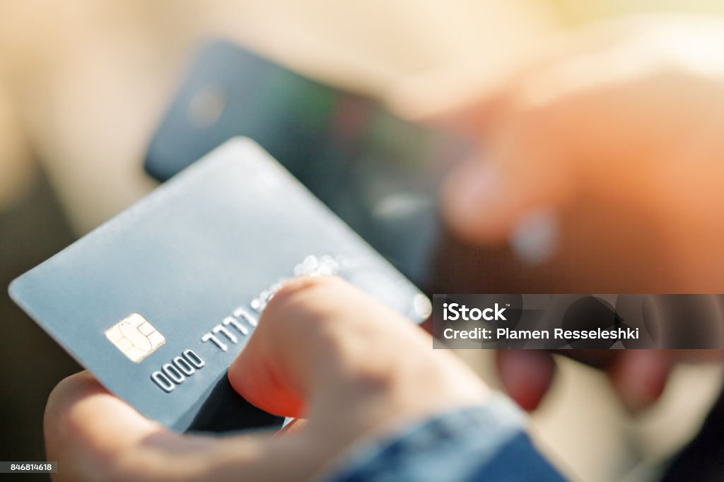A man uses a mobile phone to pay for utilities. A man uses a mobile phone to pay for utilities. Concepts of using mobile technologies and smarfon in mobile applications in the online business for payment with a credit card remotely Credit Card Stock Photo