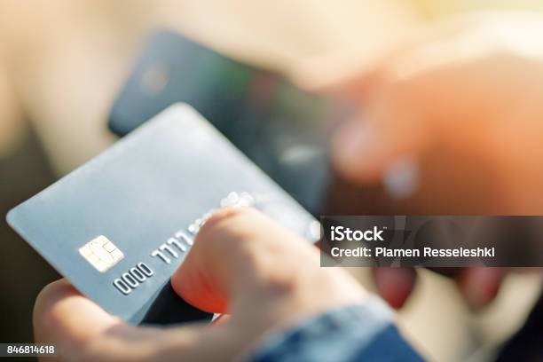 A Man Uses A Mobile Phone To Pay For Utilities Stock Photo - Download Image Now - Credit Card, Playing Card, Bank - Financial Building
