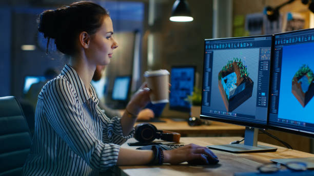 2 つのディスプレイとパソコンはレベル デザインは、女性のゲーム開発者、彼女は遅くまで仕事をし、コーヒーを飲みます。彼女は創造的なロフト オフィス スペースで動作します。 - computer programmer graphic designer graphic design studio designer ストックフォトと画像