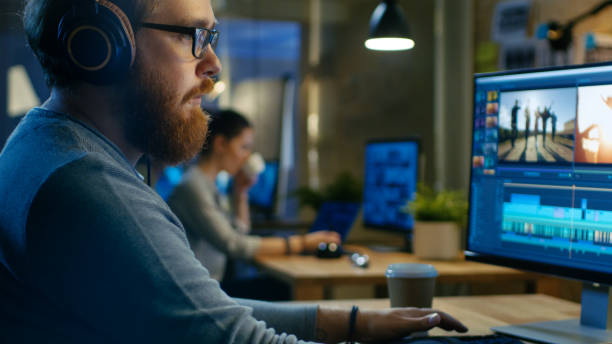 istock Male Videographer Edits and Cuts Footage and Sound on His Personal Computer, Puts on His Monitors/ Headphones. His Office is Modern and Creative Loft Studio. 846843186