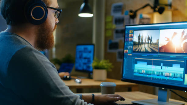 istock Male Videographer Edits and Cuts Footage and Sound on His Personal Computer, Puts on His Monitors/ Headphones. His Office is Modern and Creative Loft Studio. 846843188