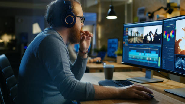 istock Male Videographer Edits and Cuts Footage and Sound on His Personal Computer, Puts on His Monitors/ Headphones. His Office is Modern and Creative Loft Studio. 846843238