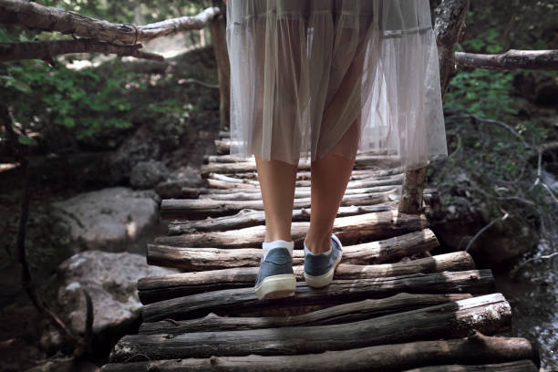 istock Girl's legs with backpack walking across hanging bridge in tropical forest 846843278